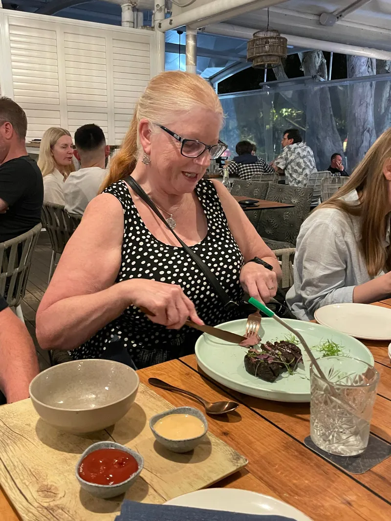 A woman cutting into her steak at the restaurant