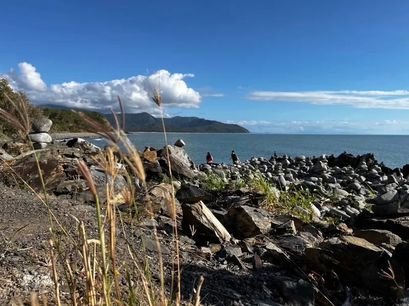Rock cairns and grasses on the headland, the coastline stretching north