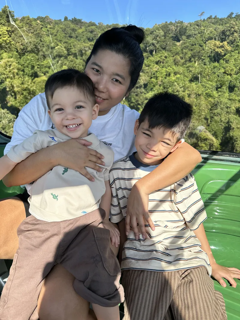 A woman hugging a toddler and a boy in a gondola