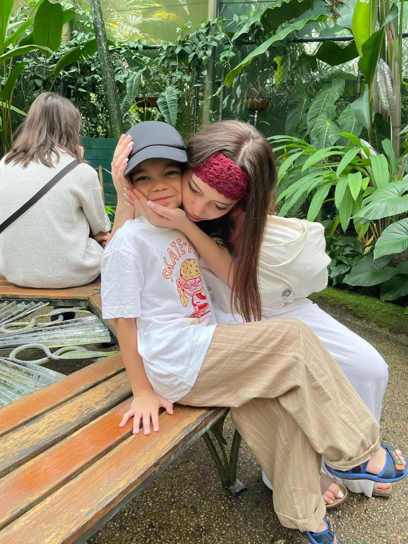 The girl squeezing the boy's cheeks on the bench
