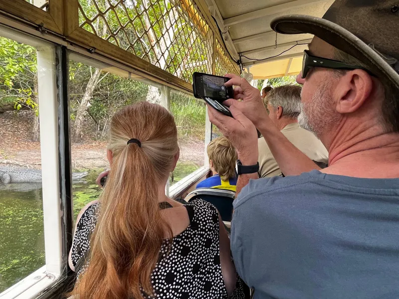 People on the boat photographing a crocodile on the bank