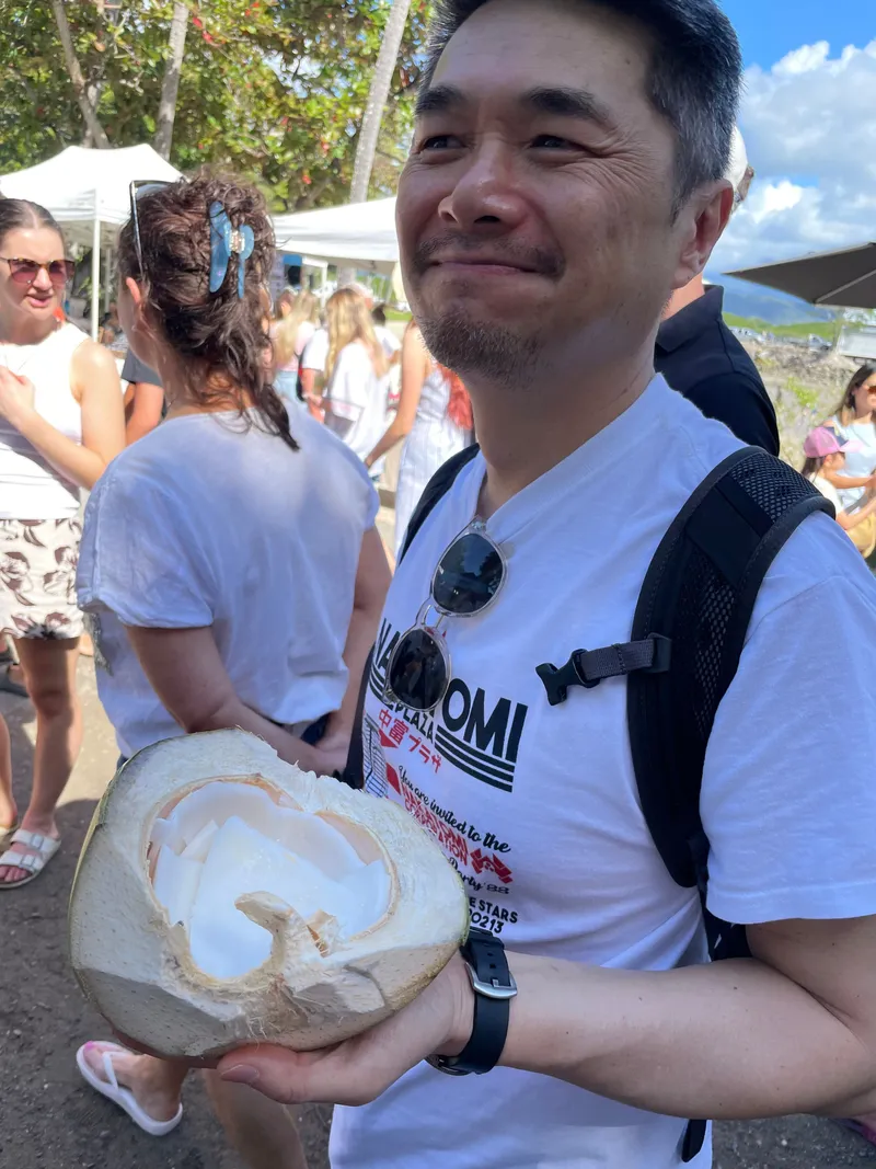 A man holding a split coconut at the markets