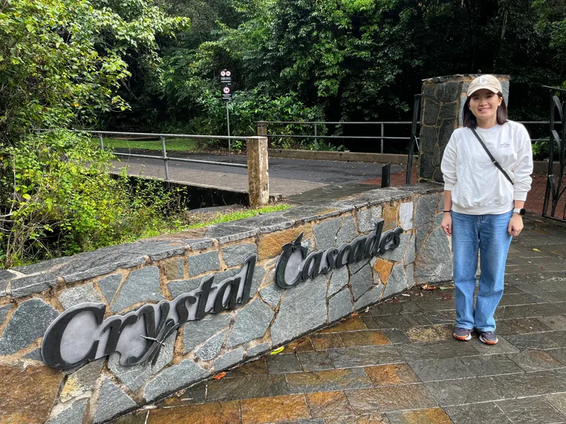 Cris in a cap standing by the stone Crystal Cascades sign
