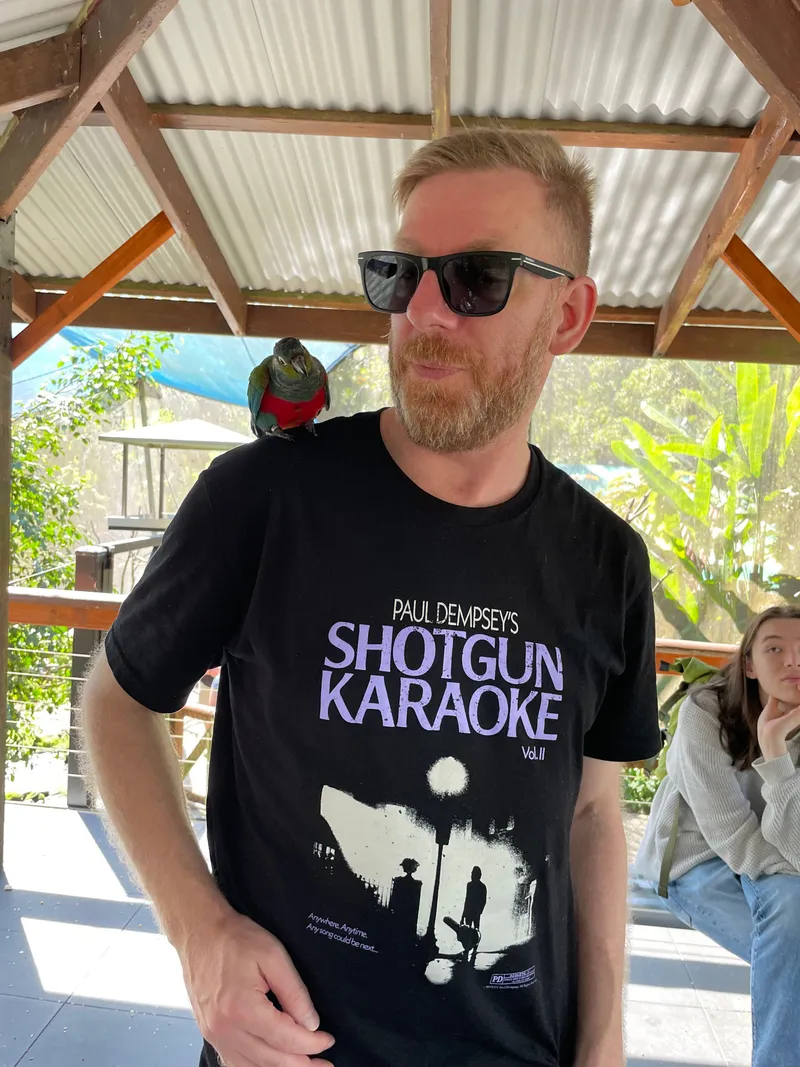 The man smiling with the parrot on his shoulder