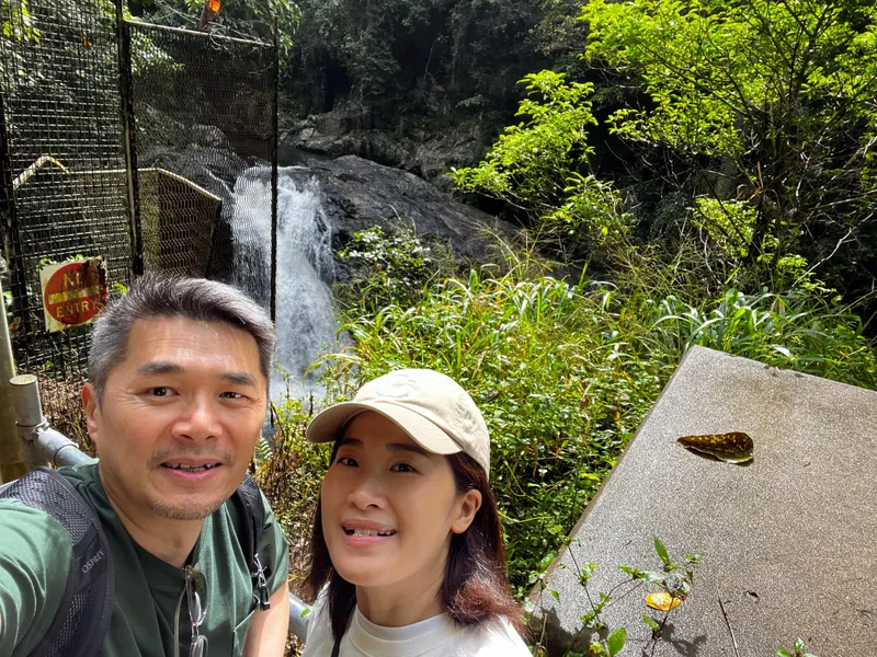 A selfie of Khon and Cris with a waterfall behind them