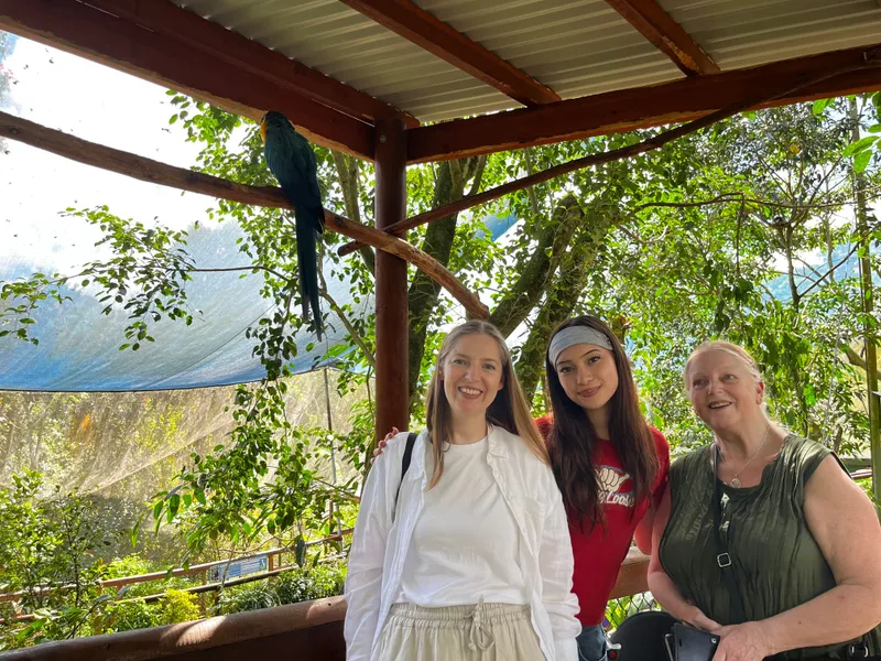 The three women smiling under the blue-and-gold macaw