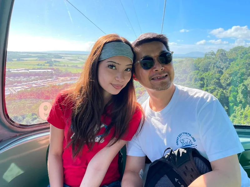 A girl and a man in a gondola, with the plain and coast behind