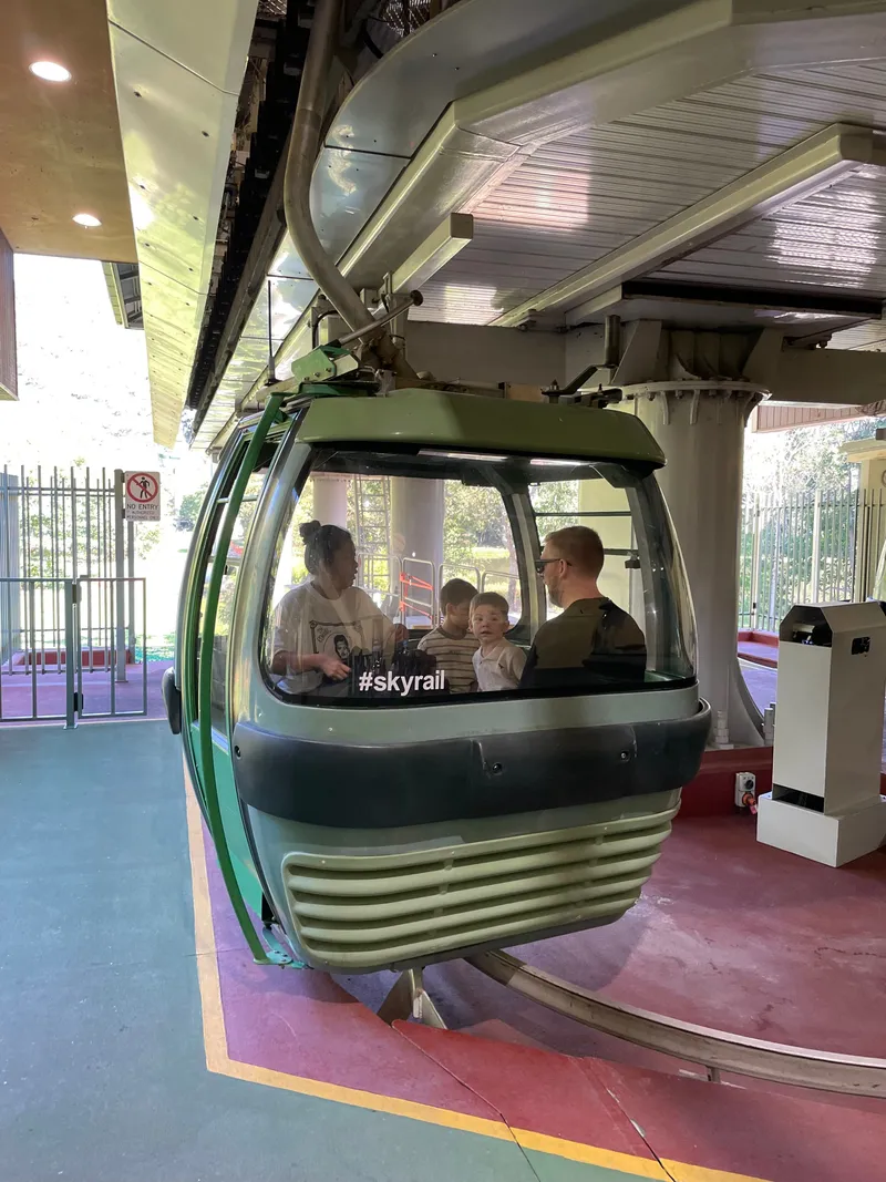 A green Skyrail gondola arriving at the station