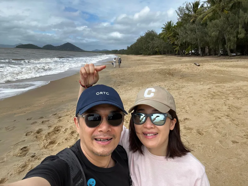 A selfie of two people on the beach, one pointing back along the sand