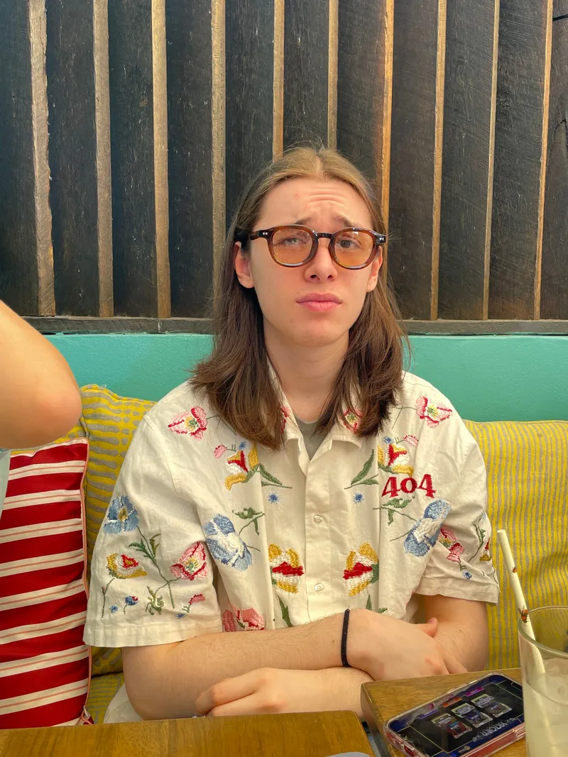 A teenager in glasses pulling a face at the table