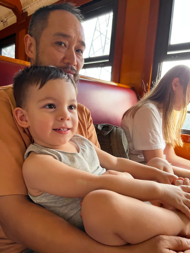 The toddler smiling on the man's lap