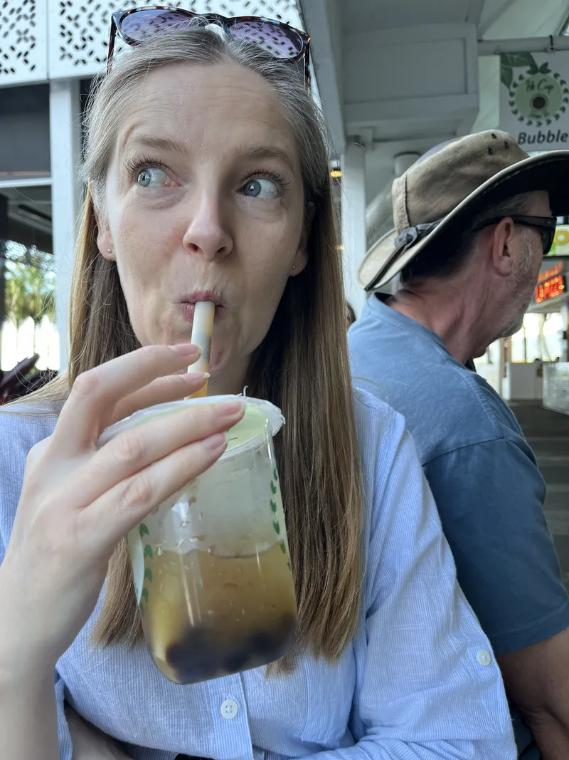 A woman sipping bubble tea, with a man in a hat beside her