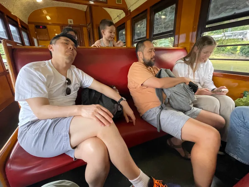 Two men and a woman resting on the red seats, with a toddler peeking over