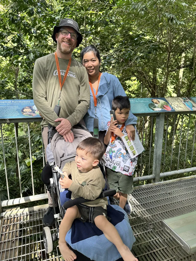 A family on a metal walkway in the forest, with a toddler in a stroller
