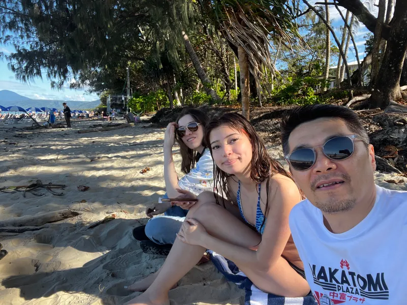 A selfie of three people sitting on the sand