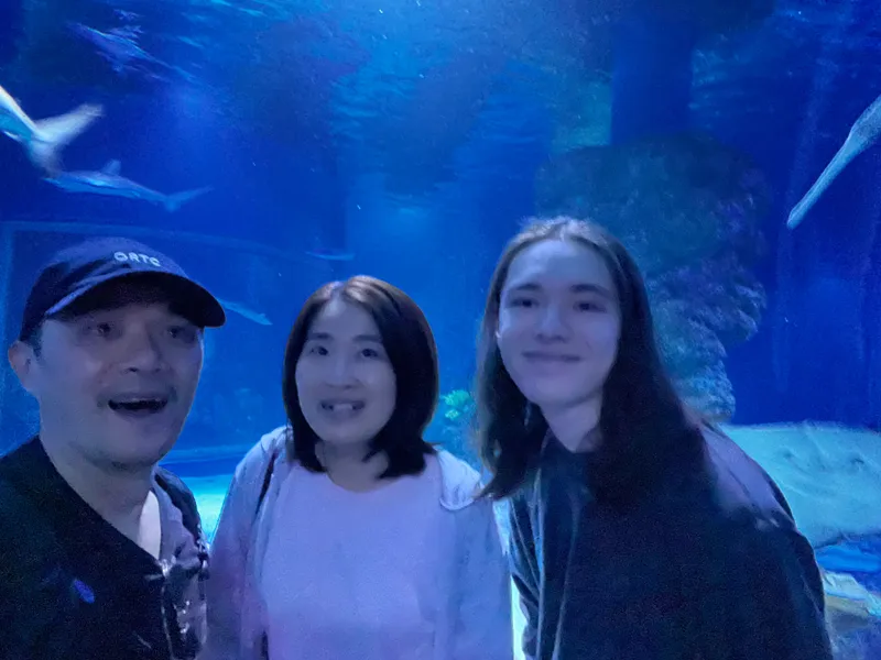 A selfie of three people in front of the shark tank
