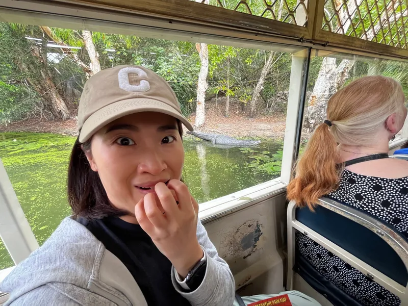 A woman on the boat with her hand to her mouth, a crocodile behind her