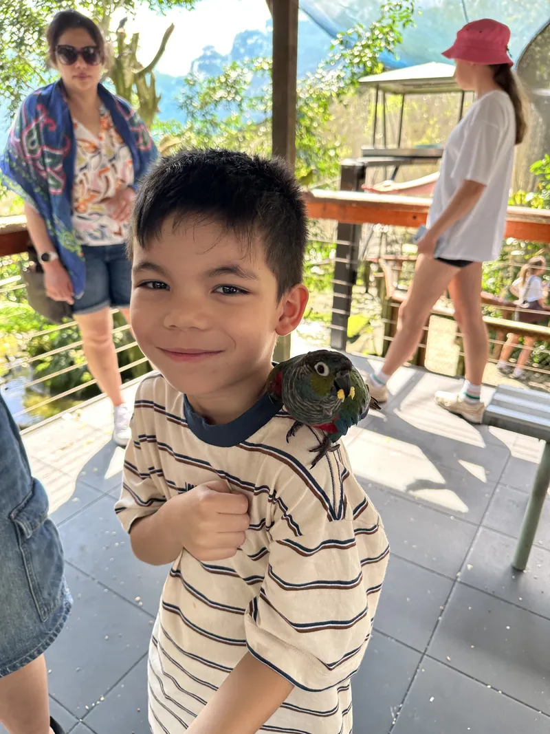 The boy beaming at the camera, the parrot still on his shoulder