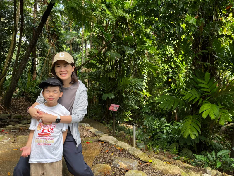 A woman hugging a boy from behind on a garden path