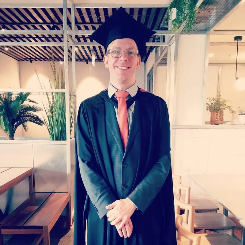 Chris in a graduation gown and cap