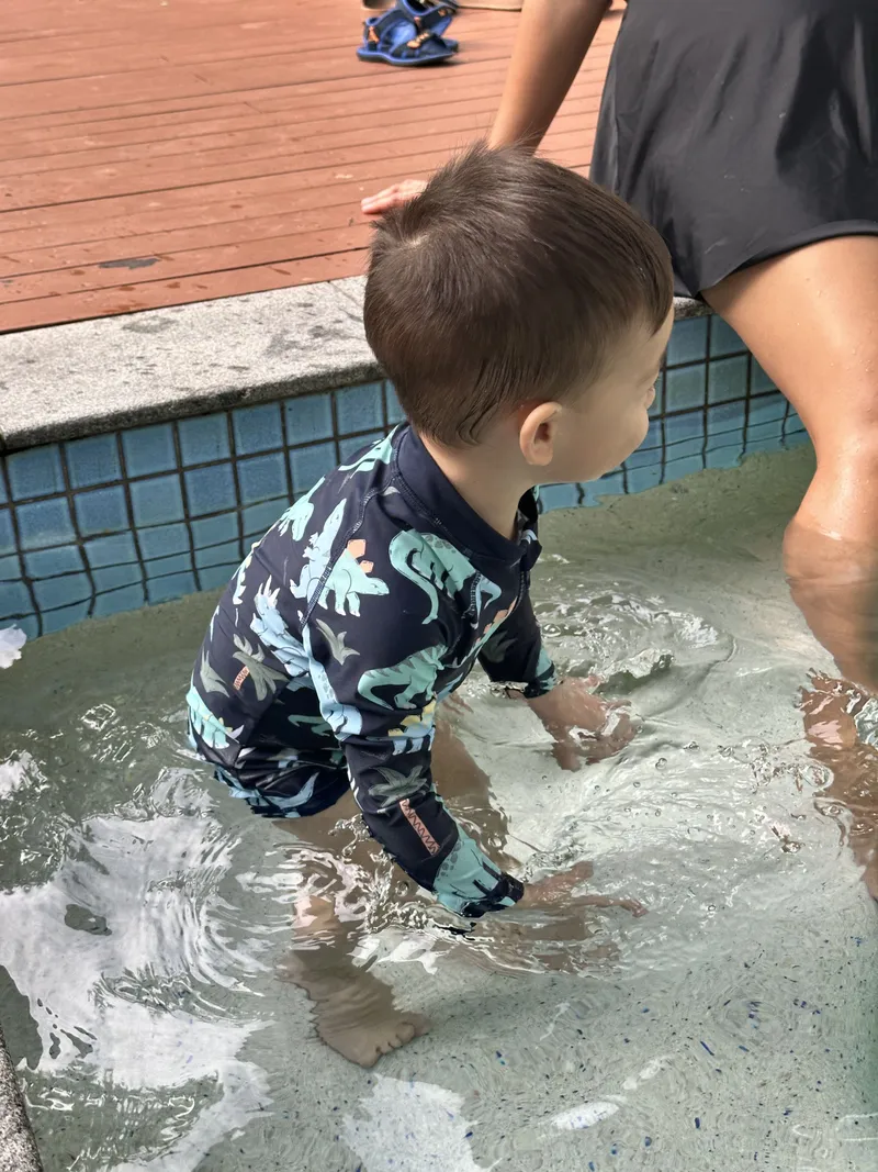 The toddler wading off along the pool step