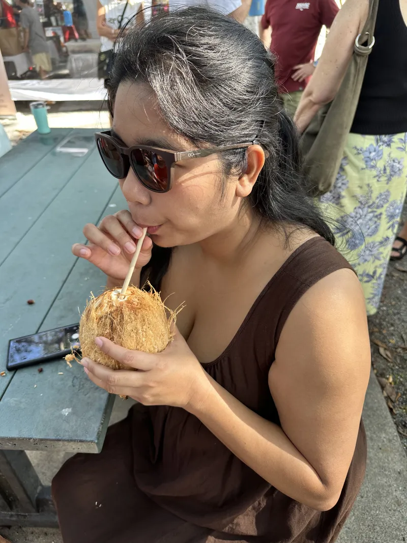 A woman sipping from a fresh coconut