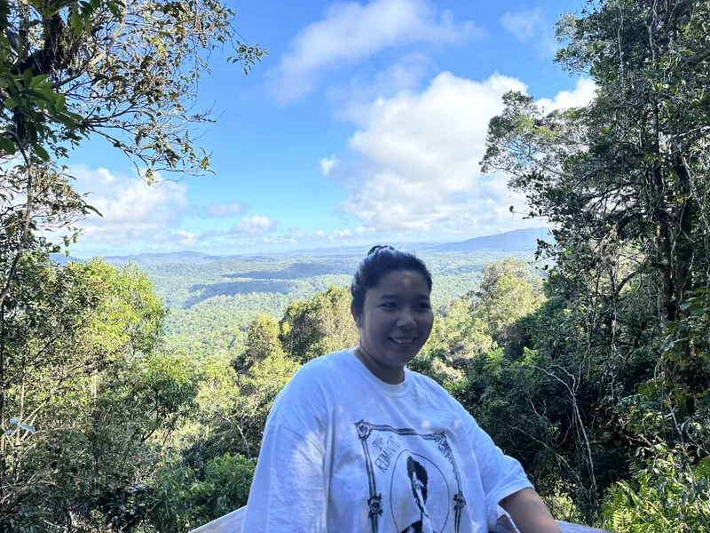 A woman at the lookout with the rainforest behind