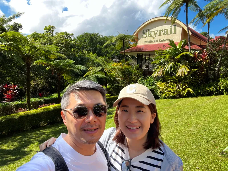 A selfie of two people at the Skyrail sign in Kuranda