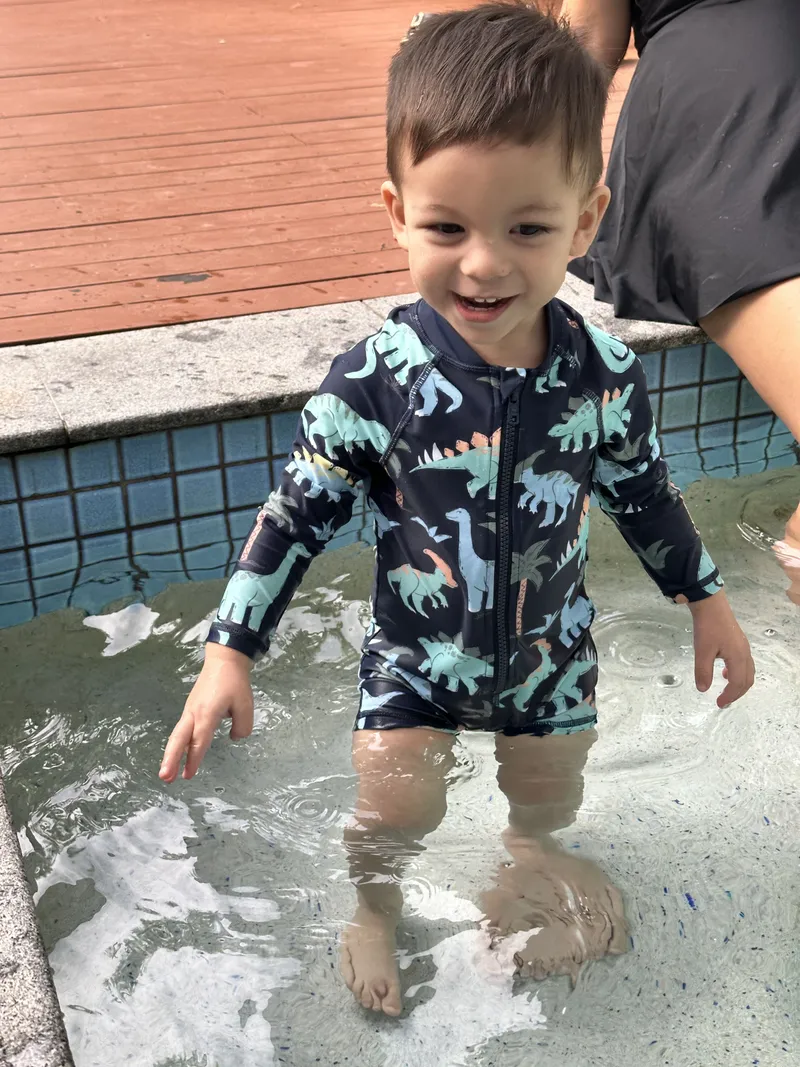 The toddler grinning in the shallow water