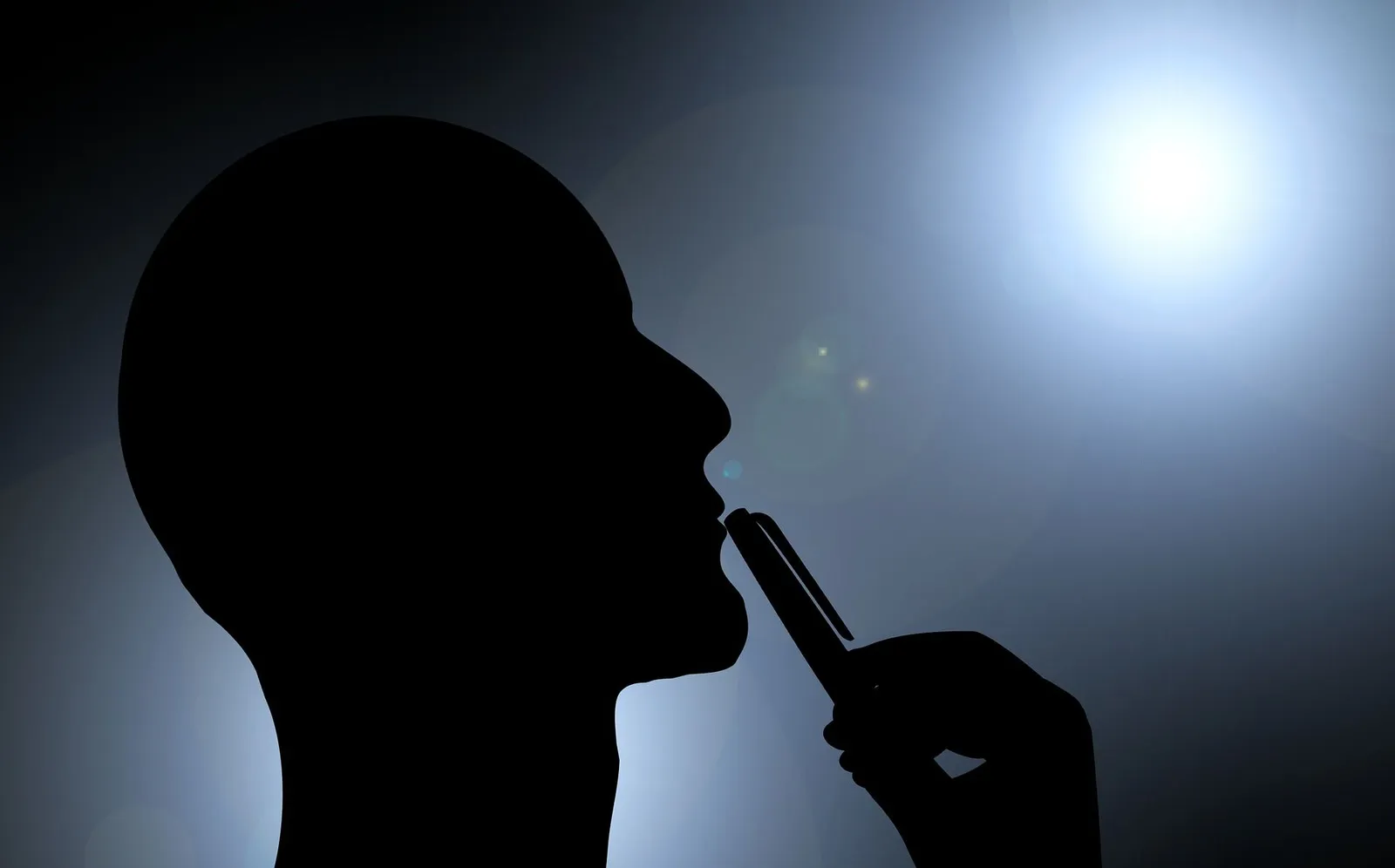 Silhouette of a man in profile, thinking, with a pen to his chin