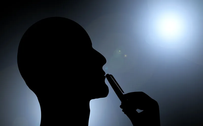 Silhouette of a man in profile, thinking, with a pen to his chin