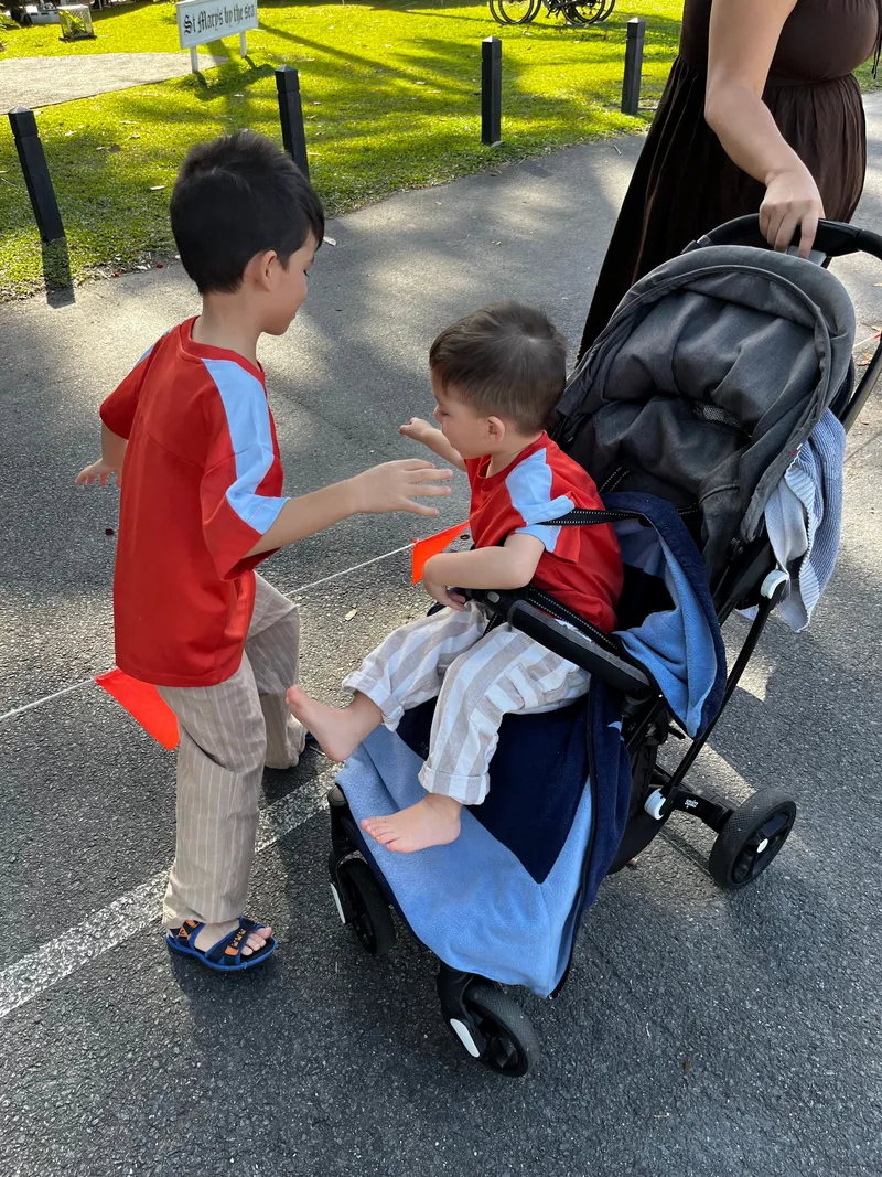 The boy playing with the toddler in the stroller