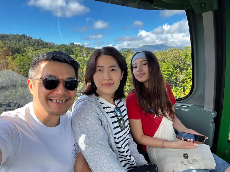 The three in the gondola, with the forest and mountains behind