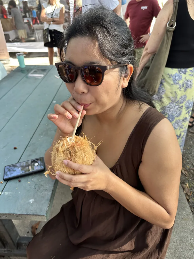 The woman drinking her coconut at a picnic table