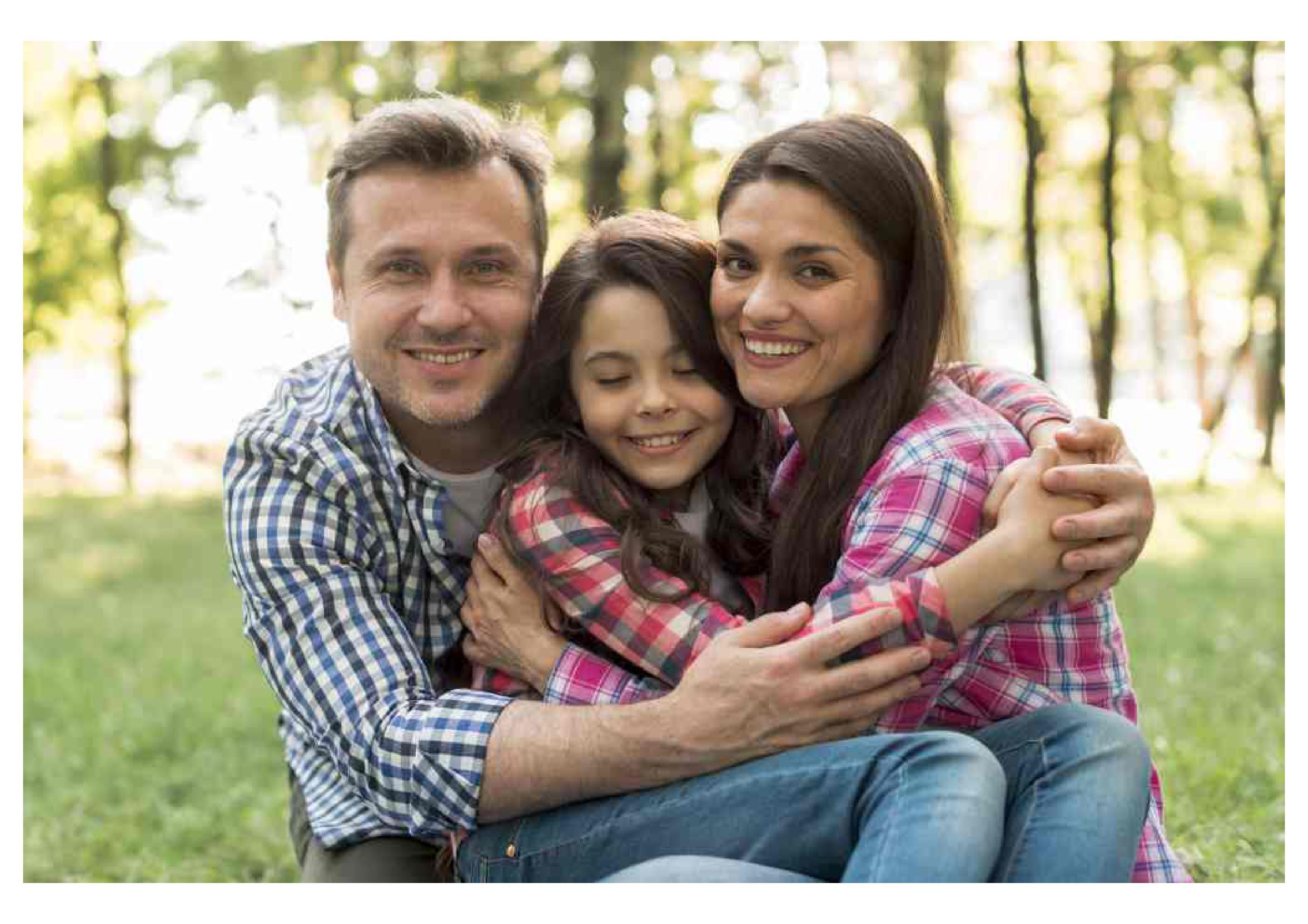 Family of three smiling and embracing outdoors