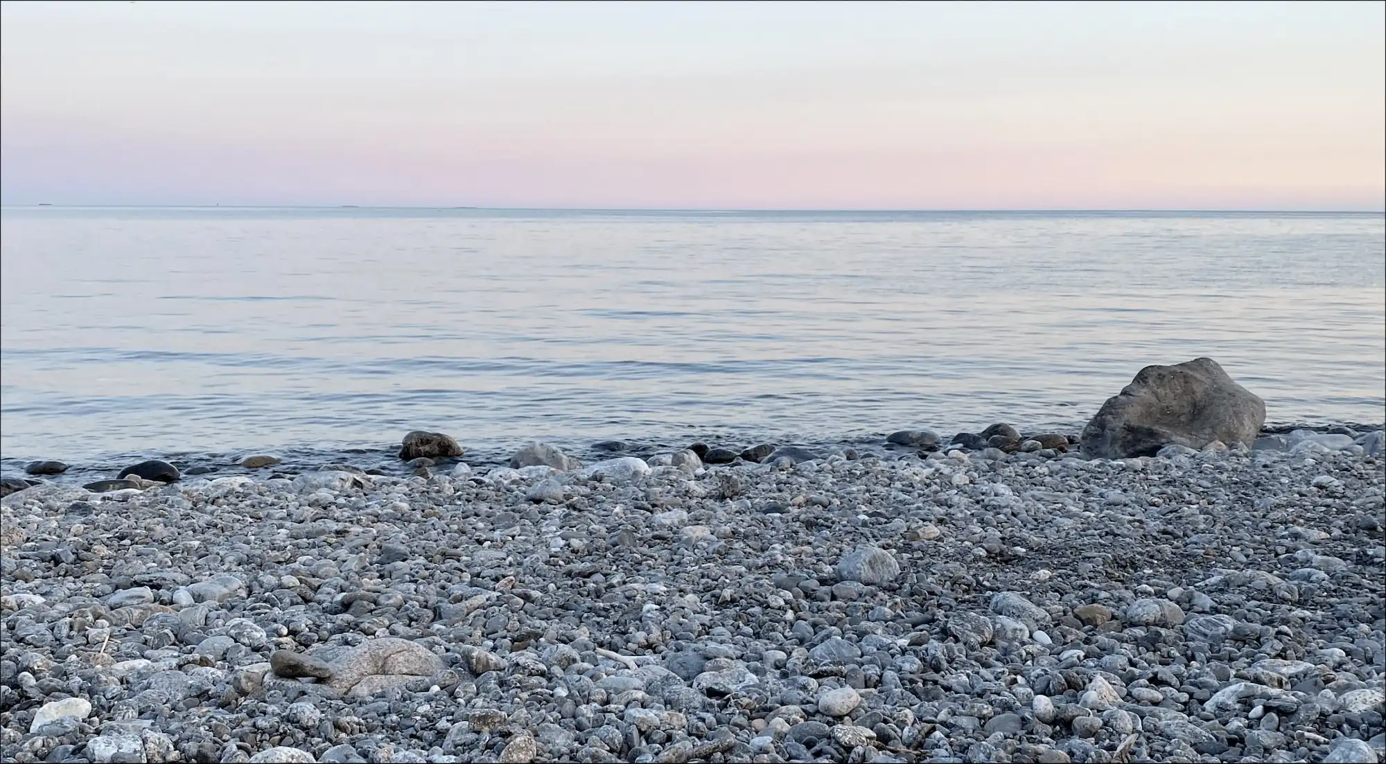 Landskapsbild på stenstrand och solnedgång
