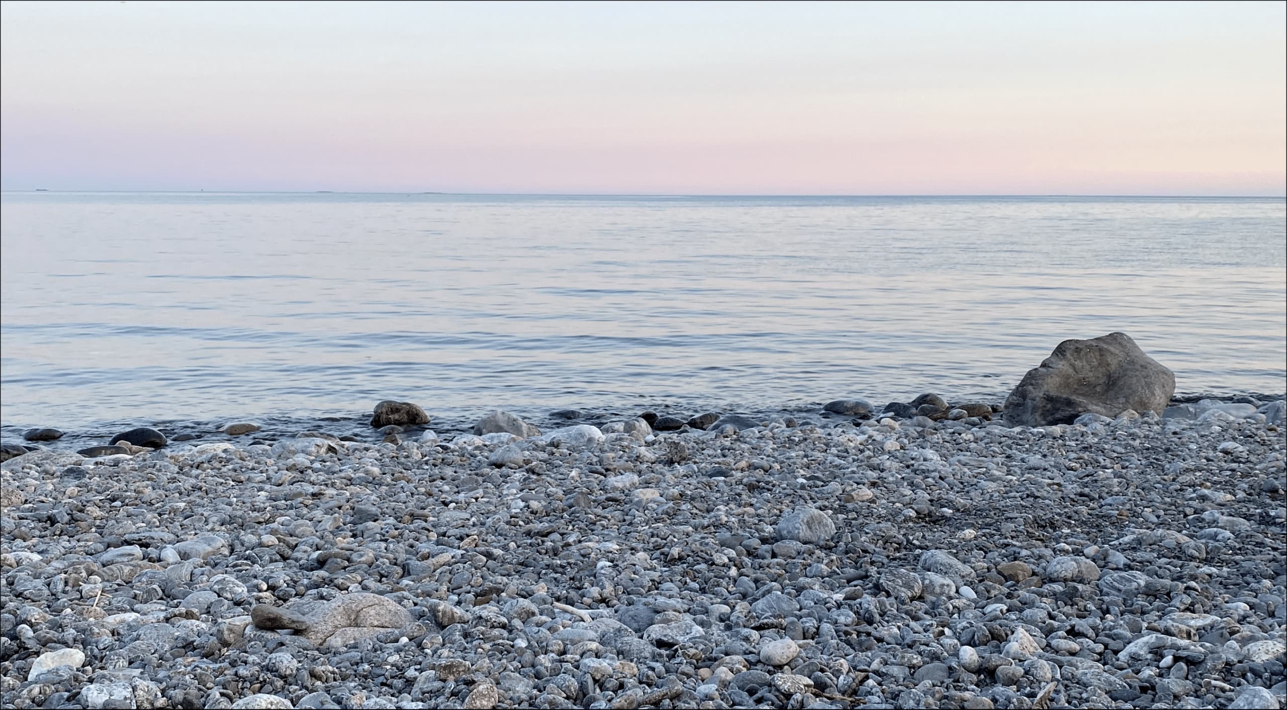 Landskapsbild på stenstrand och solnedgång