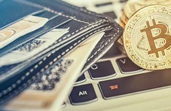 bitcoins sitting on top of a laptop and next to a wallet for online gambling