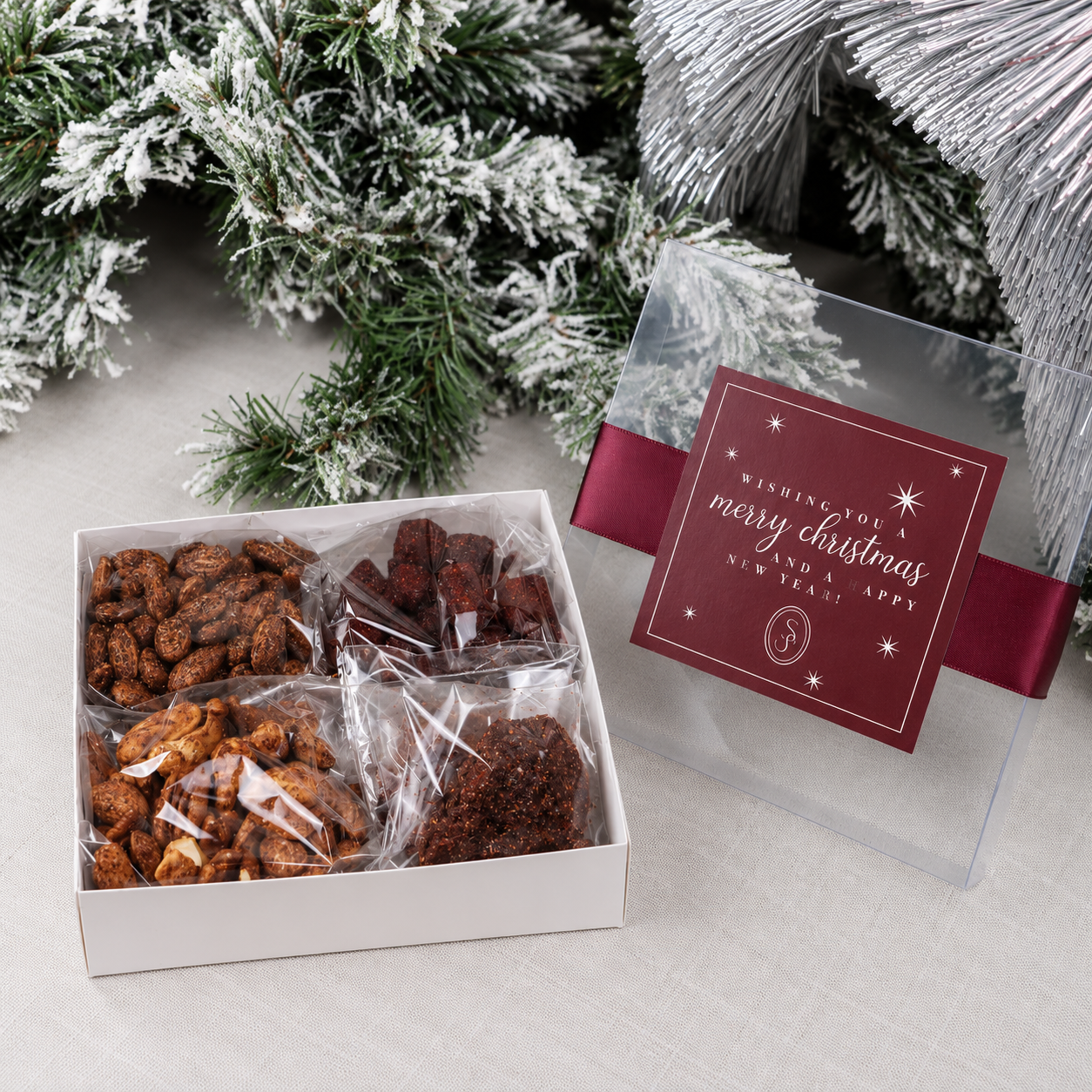 Caja navideña de regalo abierta con mix de botana enchilada con tapa transparente y lazo
