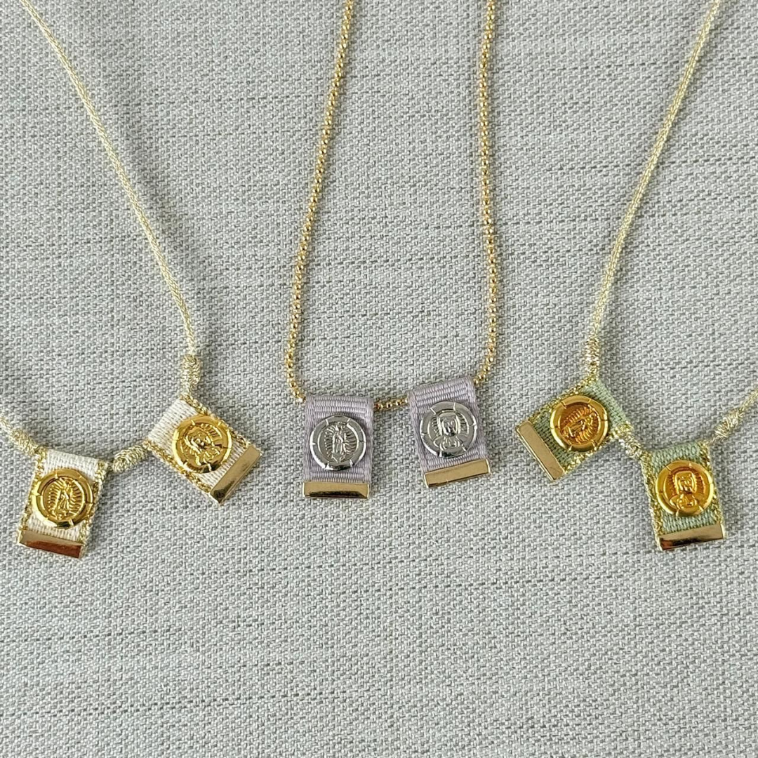 Tres collares escapularios de tela en colores crema, lila y verde con medallas religiosas