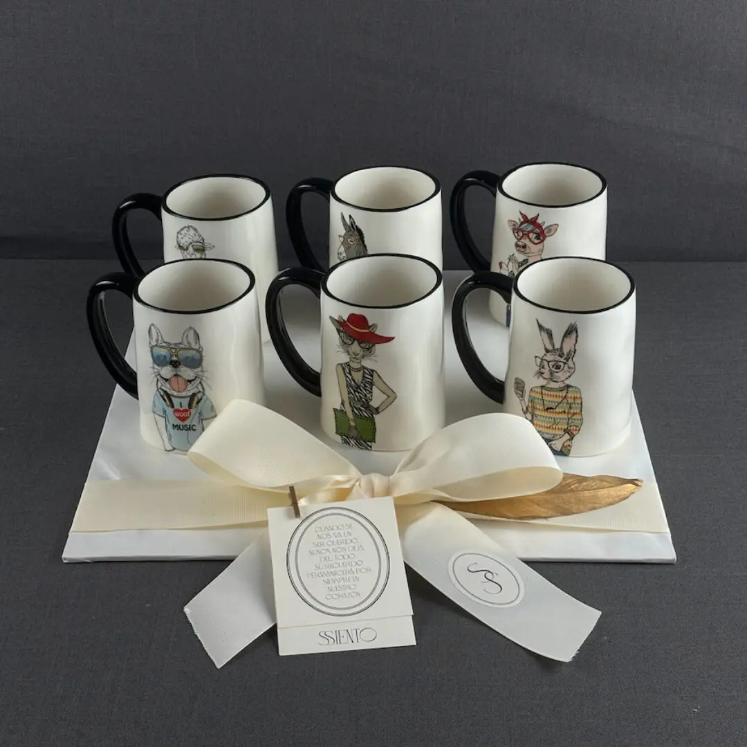 Set de tazas de cerámica blanca con asa negra e ilustraciones de animales presentadas para regalo