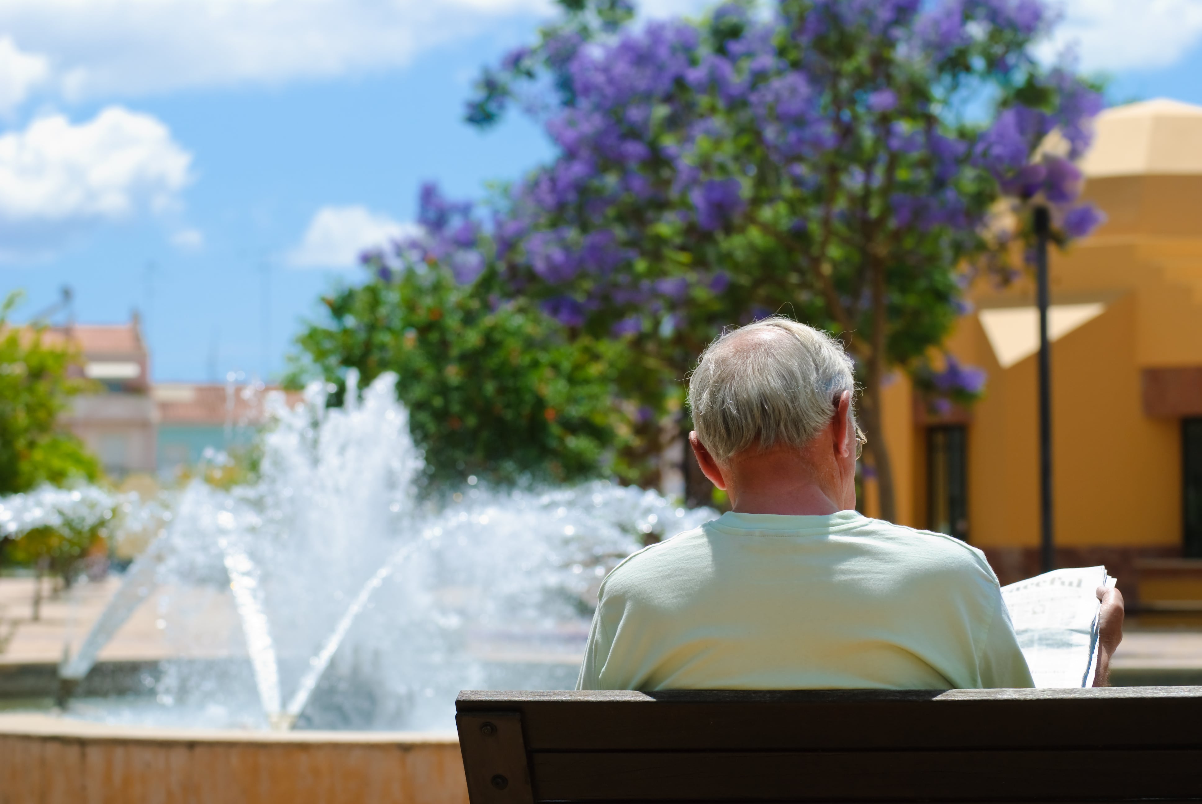 Homme lisant le journal au soleil devant une fontaine au Portugal 