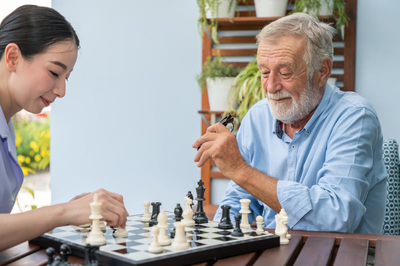 Un homme âgé jour aux échecs avec une ASH en Ehpad