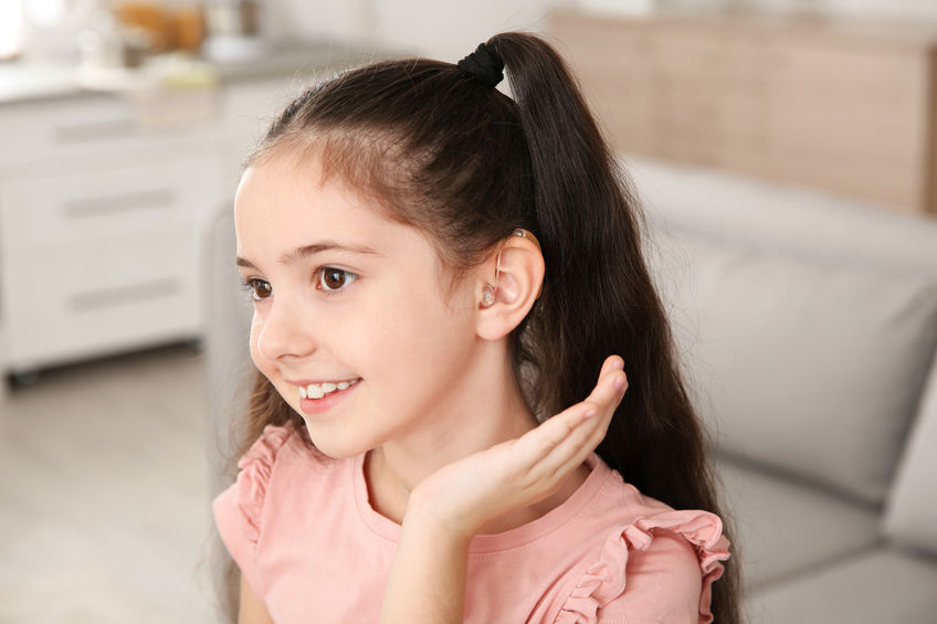 Little girl with hearing aid at home alat bantu dengar anak-anak