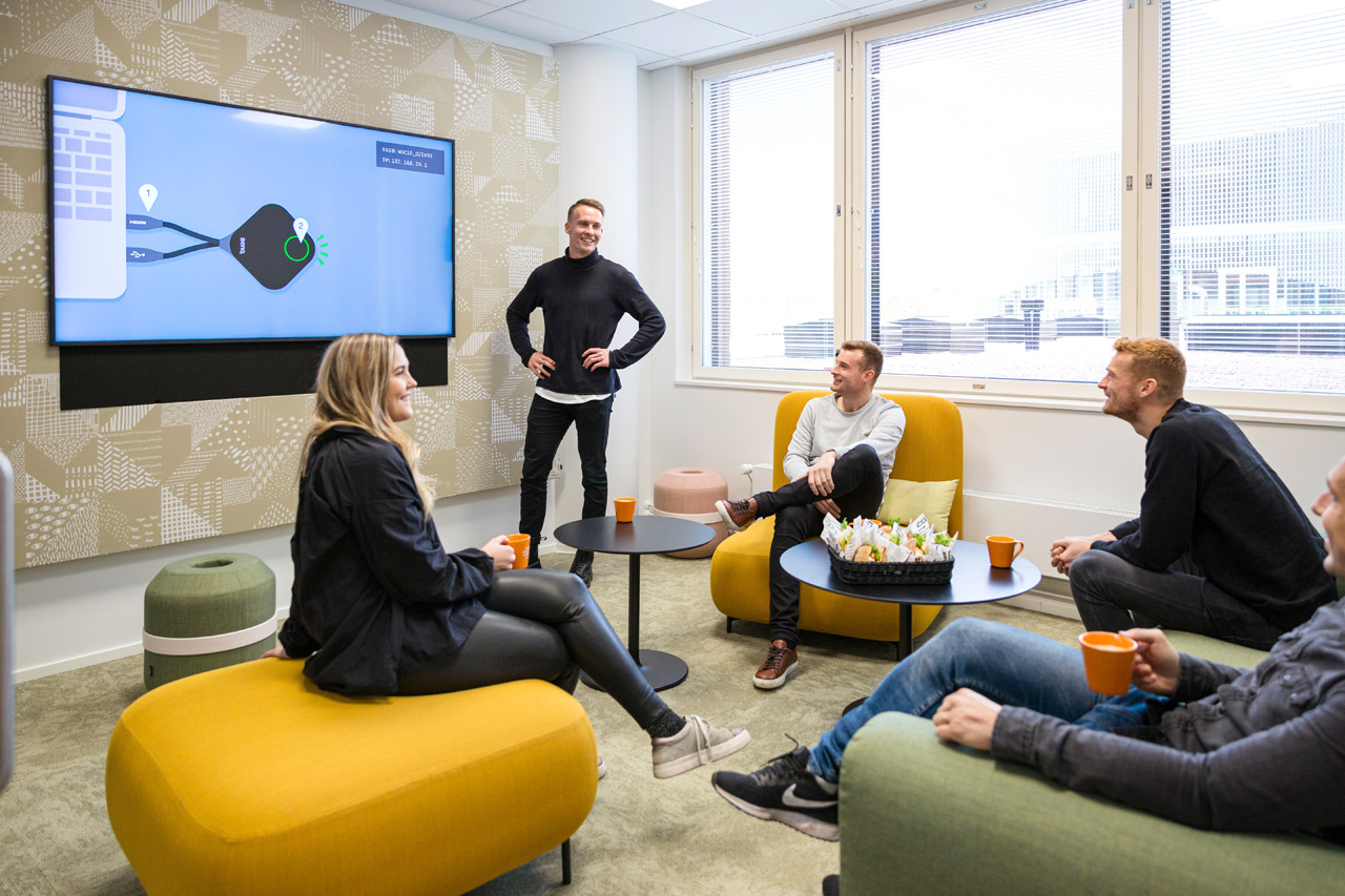 Henkilöitä Joessa kokouksessa kahvikuppien ja sämpylöiden kera