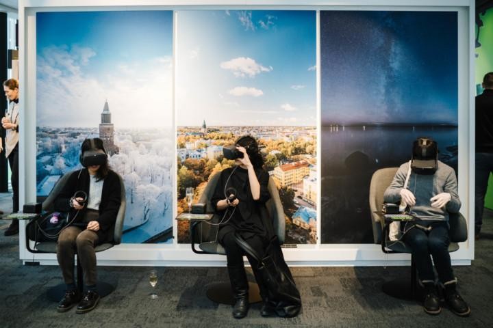 Osallistujat kokeilevat virtuaalitodellisuutta Joen Futurescapes‑kaupunkikehitystilassa, taustalla Turun kaupunkimaisemia esittävä seinäpinta