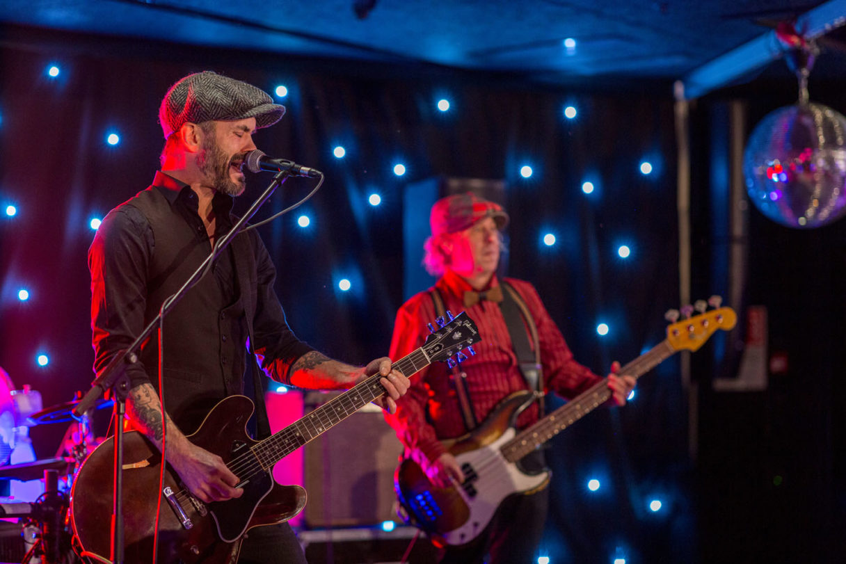 Kitaristi ja basisti esiintyvät lavalla tapahtuman live‑musiikkiosuudessa.