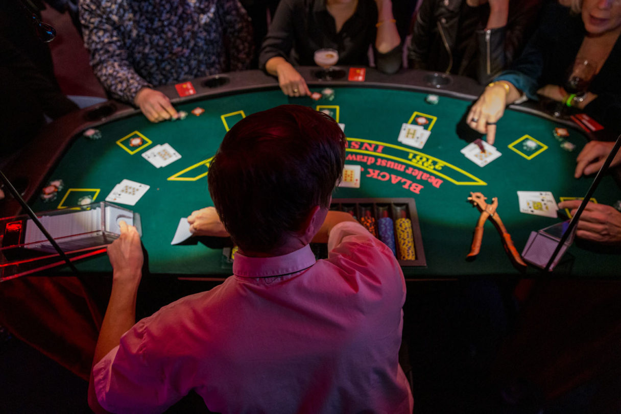 Pelaajia casino‑pöydän ääressä, jakaja jakaa kortteja viihdeohjelman aikana.