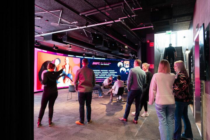 Vierailijat tutustuvat Joen Showroomiin, jossa suuri digitaalinen näyttö ja istuinryhmä esittelevät sisältöjä ja konsepteja