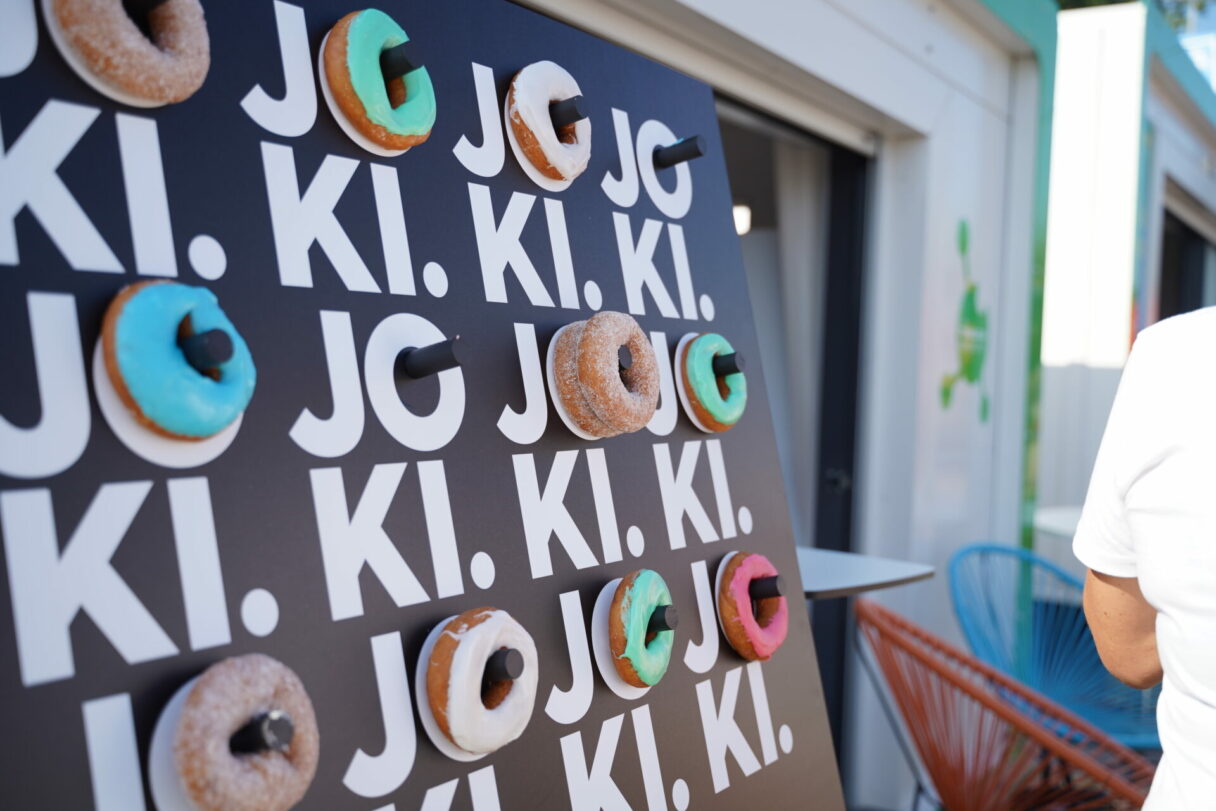 Donitsiseinä, jossa värikkäitä donitseja Joki‑brändätyllä taustalla.